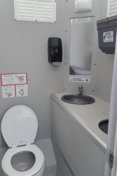 Interior de sanitario VIP con lavabo, espejo y espacio cómodo para el usuario